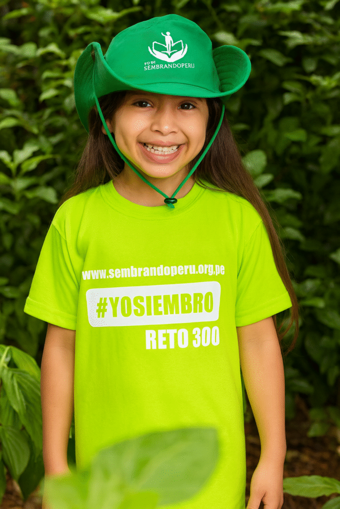 Niña sonriendo con polo verde de Sembrando Perú